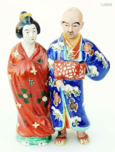 A Japanese pottery figure group, of a lady and gentleman each standing in flowing robes,