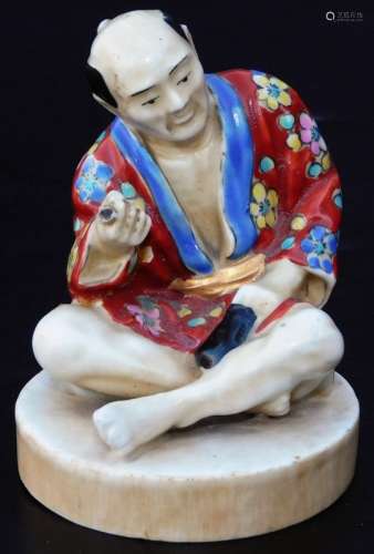 An early 20th Japanese pottery figure group, of a gentleman seated in flowing robes, florally