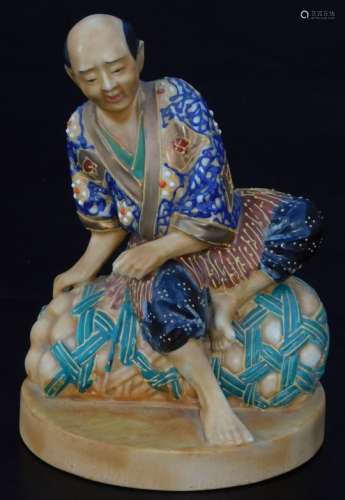 An early 20thC Japanese pottery figure, of a seated gentleman in flowing robes, polychrome decorated