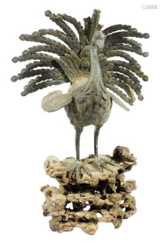 A 19thC bronze figure of a bird, with pierced and elaborate plumage, on a root carved base, 28cm