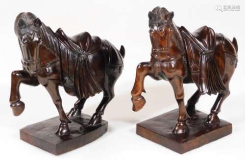 Two hardwood Chinese horses, in the Tang style, each with front legs raised on square bases, heavily