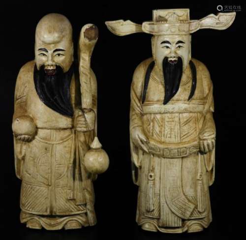 A pair of carved wooden figures of sages, one holding staff each in flowing robes, possibly with