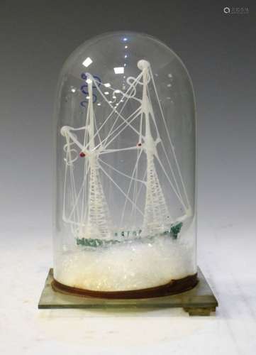 'Frigger' glass torch-blown two-masted sailing ship on rough seas, beneath glass dome, 19cm high