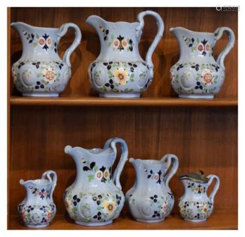 Seven various 19th Century Ironstone-type pottery jugs, each with floral decoration on pale blue