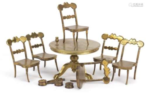 Antique brass dolls house furniture comprising table and six chairs, the table 7.5cm high x 11cm