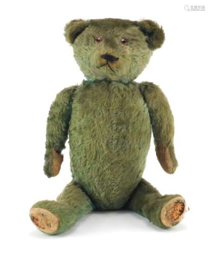 Old green straw filled teddy bear with jointed limbs, 53cm in length : For Further Condition Reports