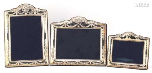 Graduated set of three silver easel photo frames by Carrs, embossed with swags, the largest 24.5cm