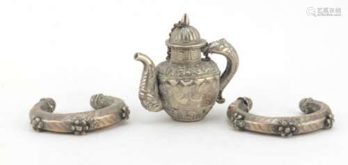Tibetan Unmarked silver miniature teapot and two silver coloured metal slave bangles, the teapot 7cm