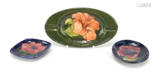 Two Moorcroft pottery pin dishes and an ashtray, each decorated with a flower head, one with paper