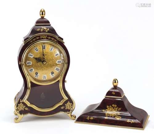 Eluxa red lacquered bracket clock with bracket, decorated with flower, having and ornate dial with