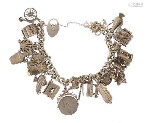 Silver charm bracelet with a large selection of mostly silver charms including fish, sewing machine,