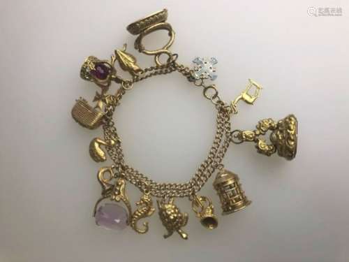A 9ct yellow gold double curb bracelet with fifteen various charms attached
