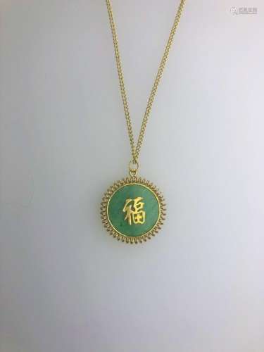 A yellow metal curb chain and pendant with inset green hardstone disk
