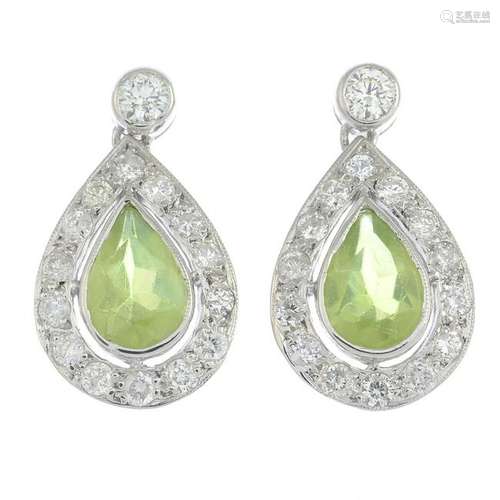 A pair of peridot and diamond earrings.Total peridot