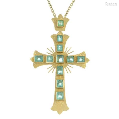 An emerald cross pendant, suspended from a cable-link