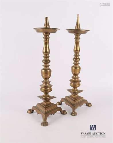 Pair of bronze candle spikes resting on a triangul…