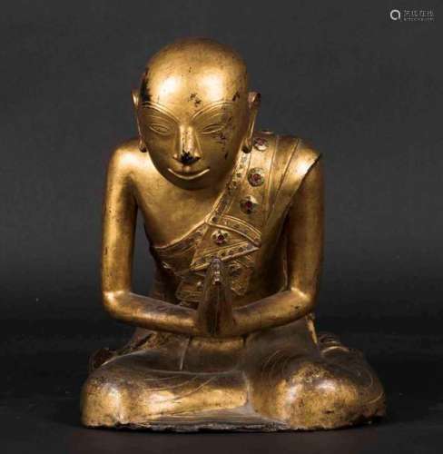 A figure of a praying monk in carved and gilt wood…