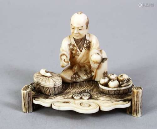 A JAPANESE MEIJI PERIOD CARVED IVORY OKIMONO OF A FRUIT SELLER, the man seated upon a carved base,