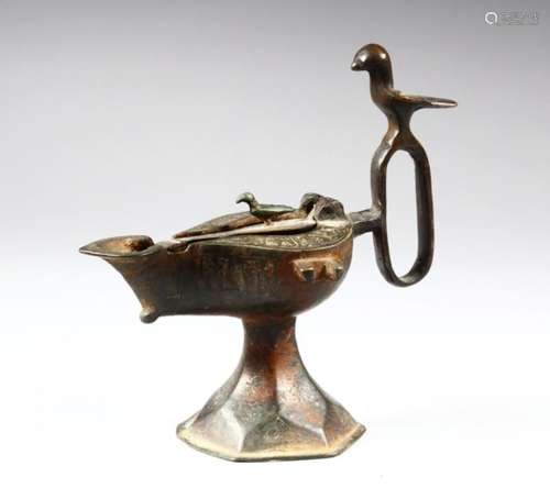 A BRONZE SELJUK LAMP, with bird shaped handle and finial, 15cm high.