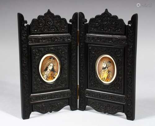 A PAIR OF INDIAN OVAL PORTRAIT MINIATURES OF A MAN AND A WOMAN, in a carved ebony folding frame,