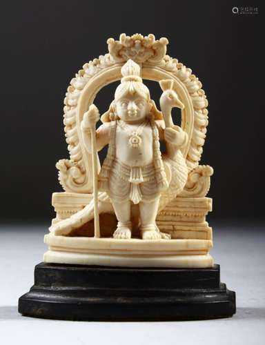 A SMALL CARVED INDIAN IVORY OF A FIGURE WITH A PEACOCK, on a wooden base, 9cm high.