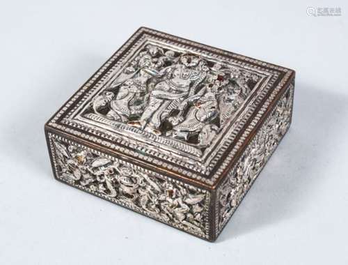 A 19TH CENTURY INDIAN SILVERED LIDDED BOX, with embossed decoration of a deity, 8cm square.