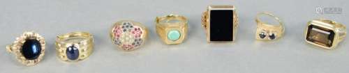 Six gold rings with stones, one with blue stone and