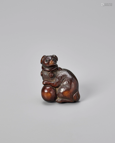 A WOOD NETSUKE OF A DOG WITH A BALL