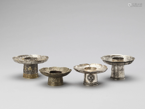 FOUR SINO-TIBETAN SILVER PARCEL-GILT CANDLE …