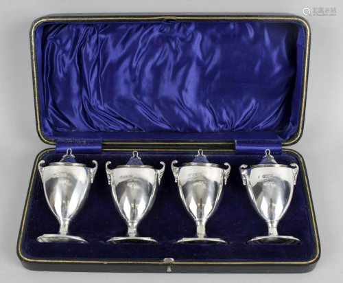 A cased set of four silver pepper pots, each of urn