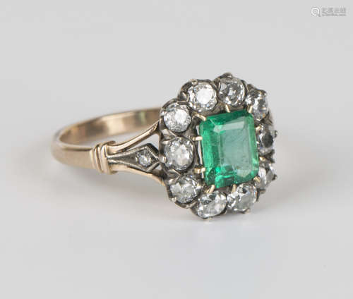 An 18ct gold, emerald and diamond cluster ring, claw set with an emerald cut emerald within a