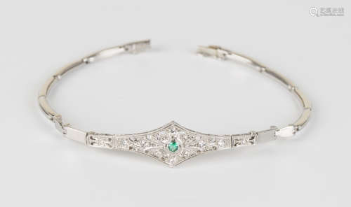 A white gold, emerald and diamond bracelet, the lozenge style front in a pierced scroll design,
