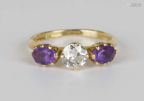 An 18ct gold, diamond and amethyst three stone ring, claw set with the cushion cut diamond between