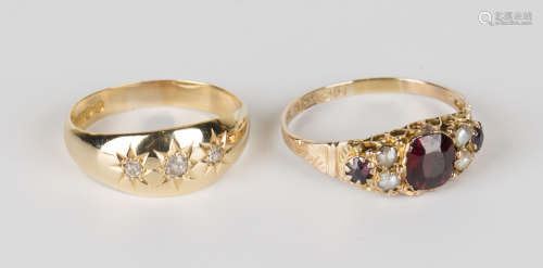 A 9ct gold, garnet and half-pearl ring, claw set with a cushion cut garnet between half-pearl sides,