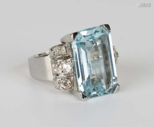 An aquamarine and diamond ring, claw set with an emerald cut aquamarine between curved shoulders,