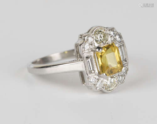 A platinum, yellow sapphire and diamond ring, claw set with an emerald cut yellow sapphire within