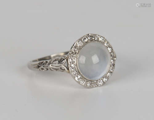 A moonstone and diamond ring, collet set with a circular cabochon moonstone within a surround of