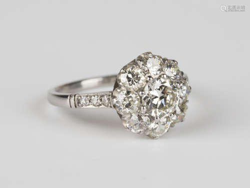 A platinum and diamond cluster ring, claw set with the principal circular cut diamond within a