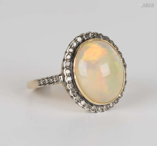 A gold, silver, opal and circular cut diamond ring, mounted with an oval opal within a diamond