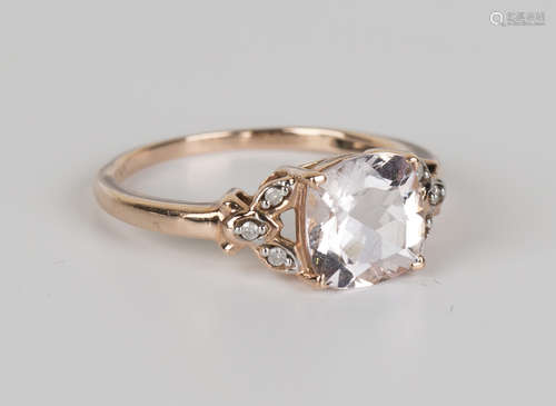 A 9ct gold ring, claw set with a cushion cut morganite between diamond set three stone pierced