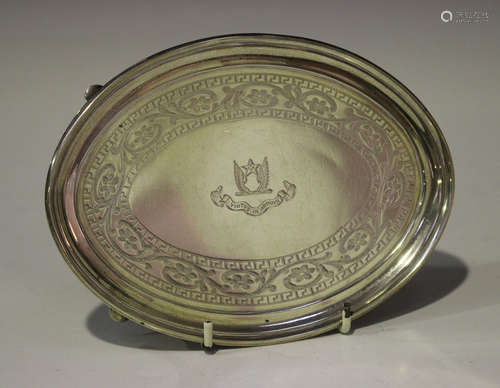 A George III Irish silver oval teapot stand, engraved with a foliate scroll and keyfret border, on