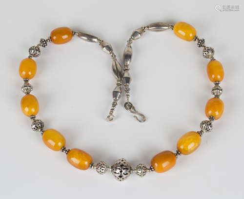 An amber necklace of ethnic design with ten vari-coloured oval amber beads mounted at intervals,