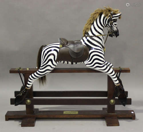 A zebra rocking horse with black eyes, mane, tail and leather saddle, raised on a wooden stand