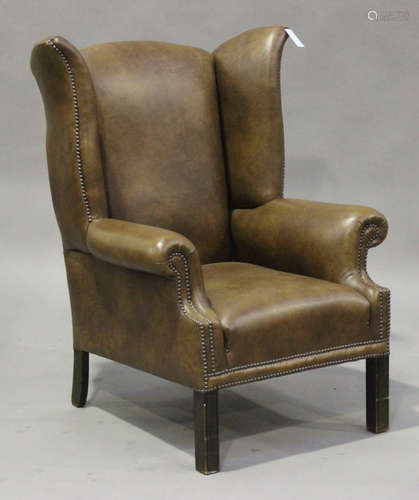 A 20th century George III style brown leather wing back armchair with brass studwork decoration,