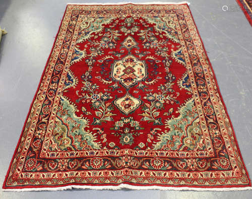 A Central Persian rug, mid-20th century, the red field with a lobed medallion, supported by