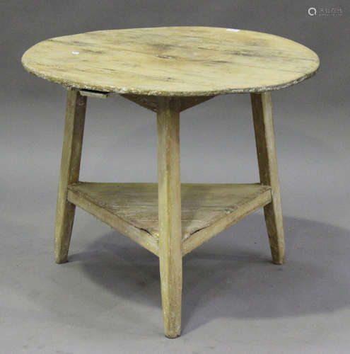 A 19th century stripped pine cricket table, the circular top raised on three square tapering legs