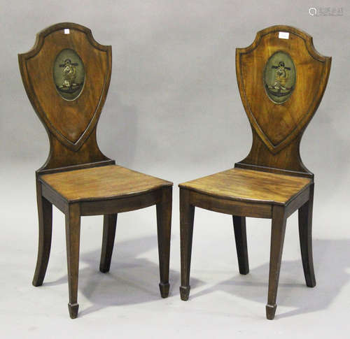 A pair of 19th century mahogany shield back hall chairs, each back inset with an oval panel