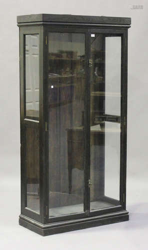 An early 20th century black painted shop display cabinet, fitted with a pair of glazed doors, on a