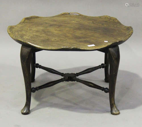 An early 20th century provincial style elm and stained beech occasional table, the slightly dished