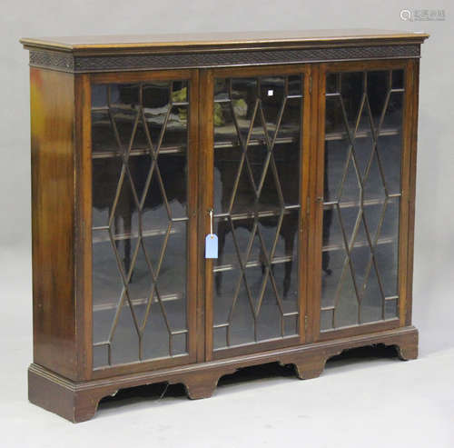 An Edwardian mahogany bookcase, the blind fretwork frieze above three astragal glazed doors